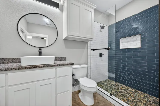 a bathroom with a granite countertop toilet sink and mirror