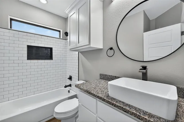 a bathroom with a granite countertop toilet a sink and bathtub
