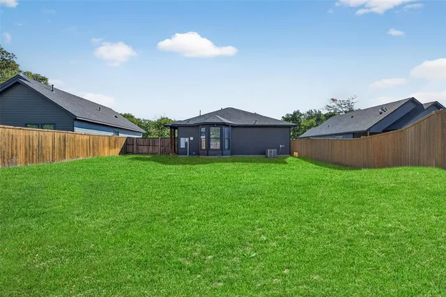 a view of a yard in front of a house with a large tree