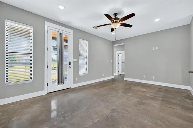 a view of an empty room with a ceiling fan and window