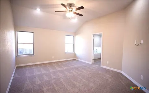 an empty room with windows and fan