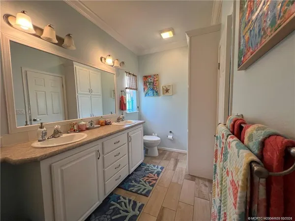 a spacious bathroom with a double vanity sink a toilet and a mirror