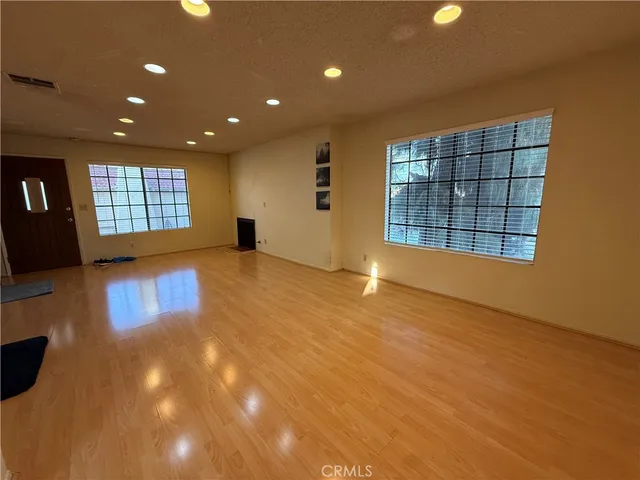 a view of an empty room with wooden floor and windows