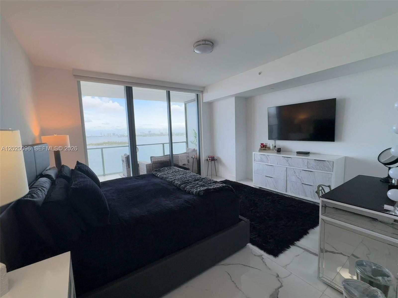 788 Northeast 23rd Street, Unit 1202 Miami, FL 33137 - Photo 17 of 64 a bedroom with a bed and a flat tv screen on the dresser