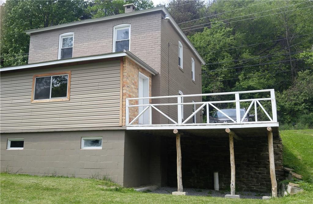 Rear of home showing off-street parking, beautiful brickwork on side entry, and poplar beams supporting deck that overlooks back yard.