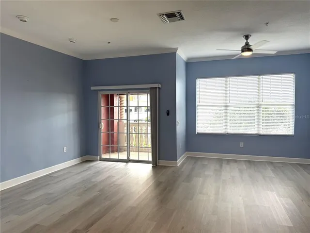 an empty room with wooden floor and windows