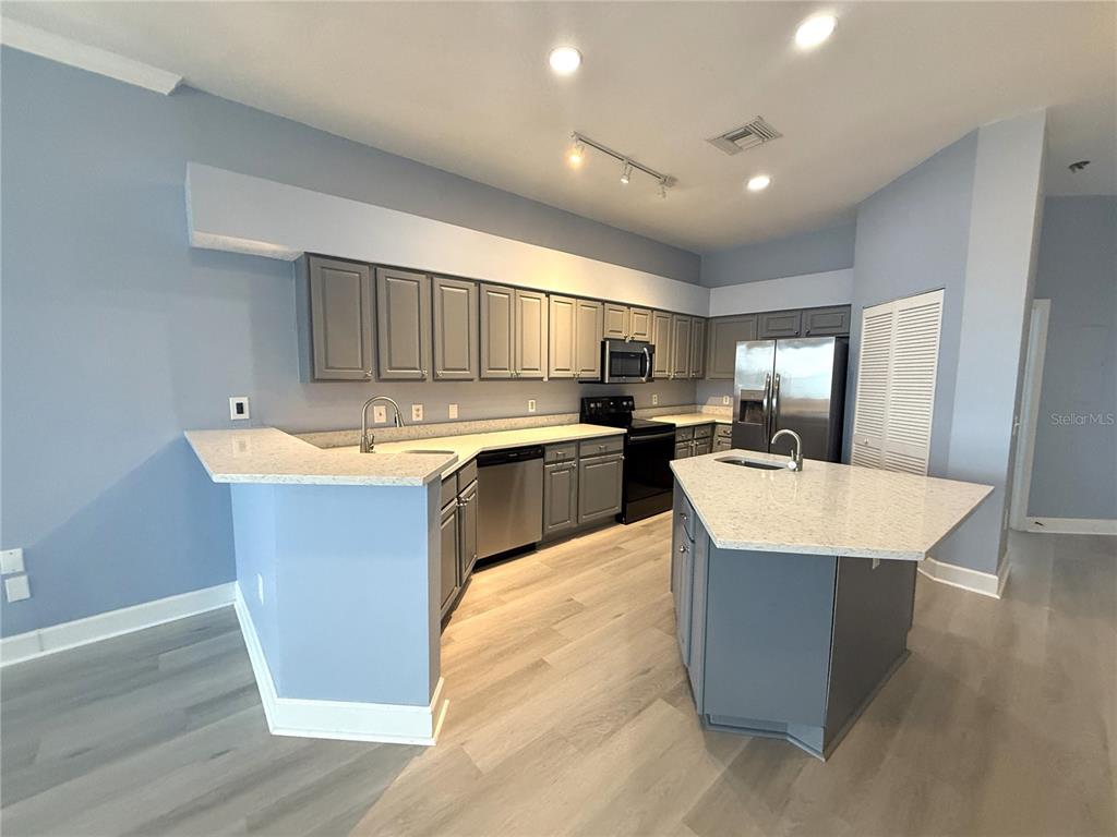 116 131st Avenue East, Unit C Madeira Beach, FL 33708 - Photo 8 of 41 a large kitchen with kitchen island a sink dishwasher stove with wooden floor and cabinets