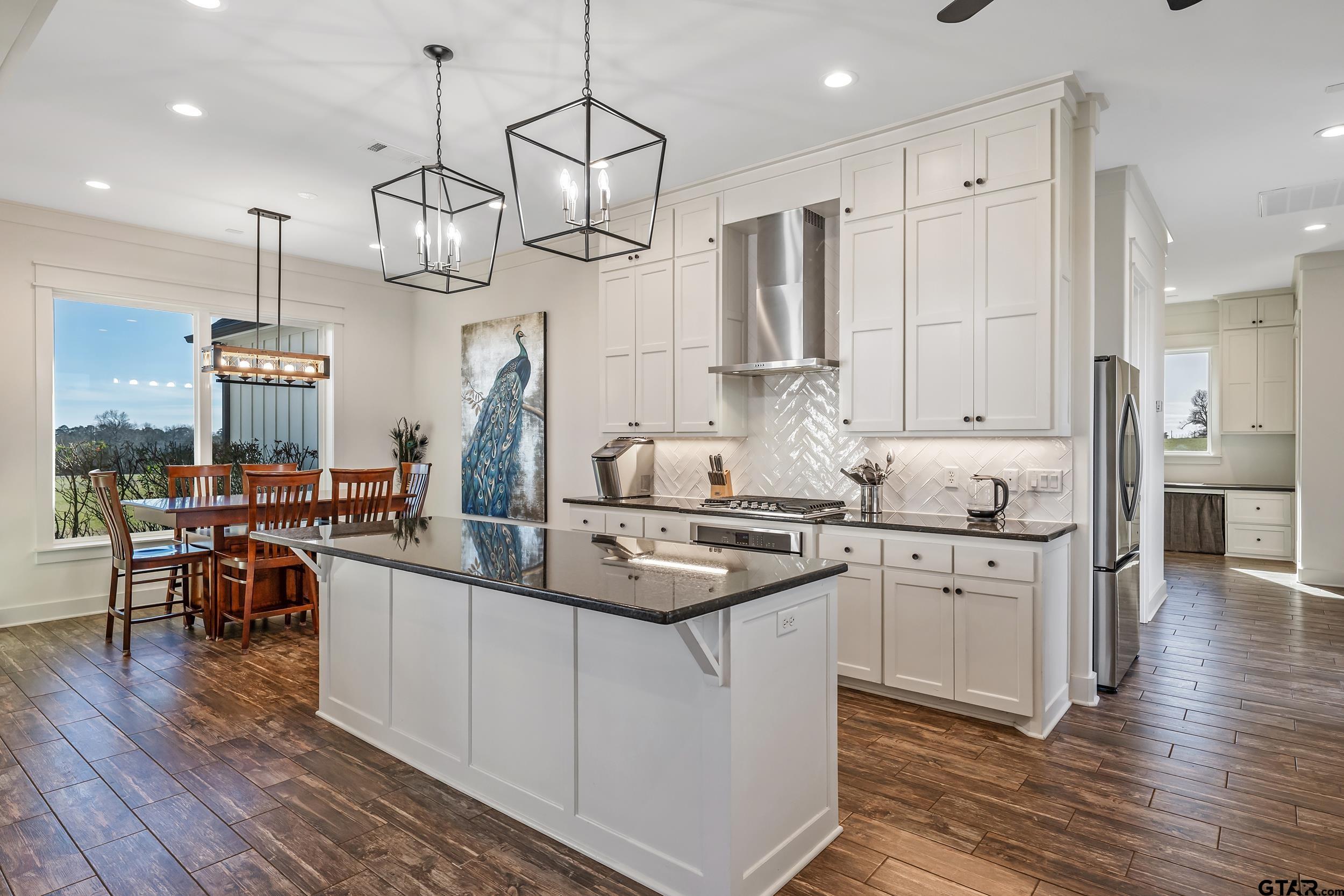 223 Riata Road Bullard, TX 75757 - Photo 10 of 45 a kitchen with stainless steel appliances kitchen island granite countertop a sink a stove and a wooden floor
