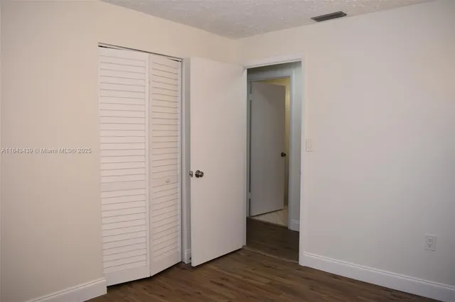 an empty room with wooden floor and closet