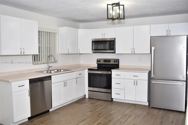 a kitchen with white cabinets and stainless steel appliances