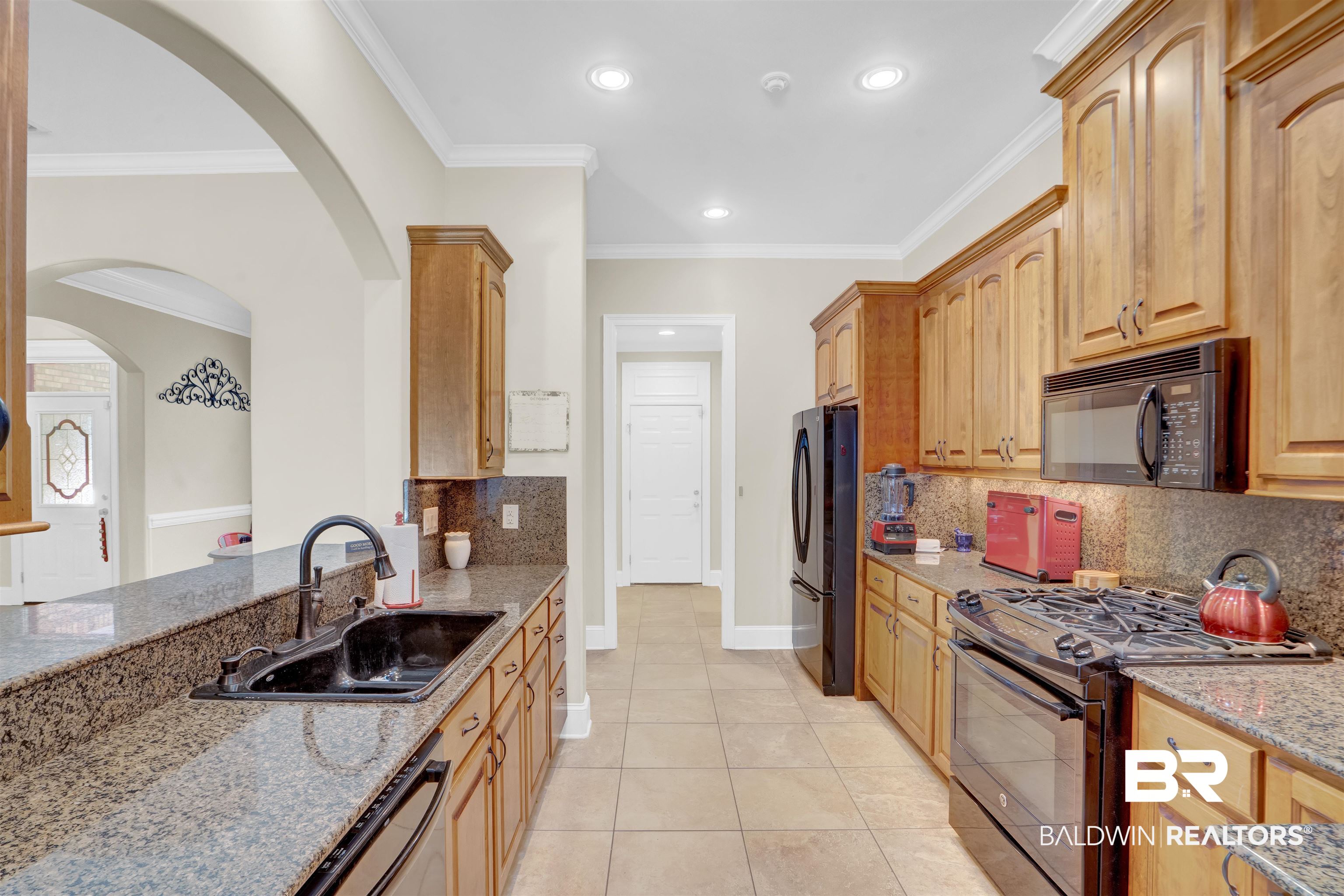 10951 Driver Court Fairhope, AL 36532 - Photo 22 of 46 Kitchen with light tile patterned floors, sink, ornamental molding, black appliances, and light stone countertops
