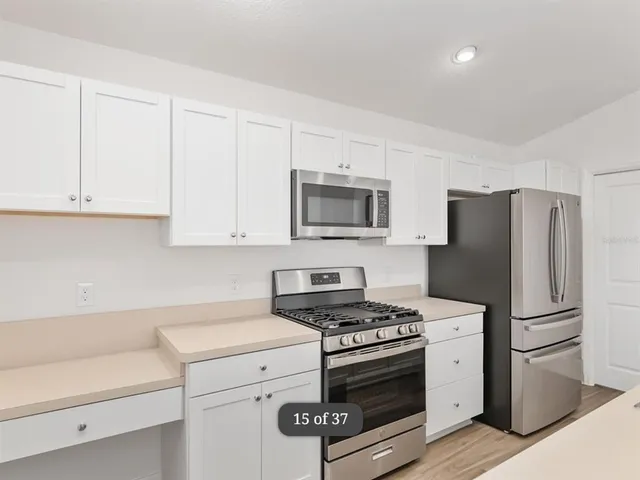 a kitchen with white cabinets and stainless steel appliances