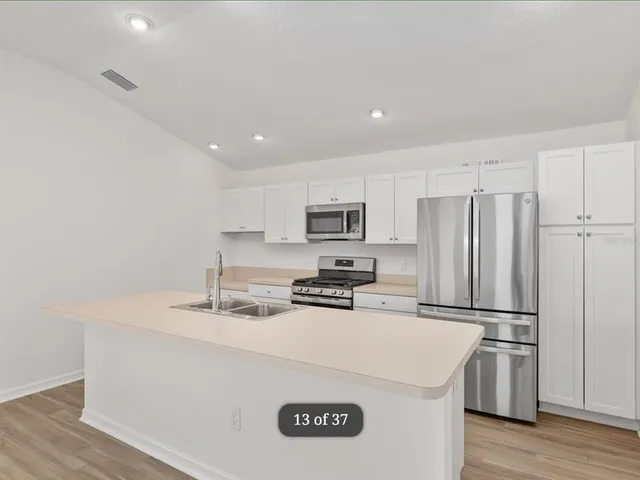 a kitchen with stainless steel appliances a refrigerator sink stove and wooden floor