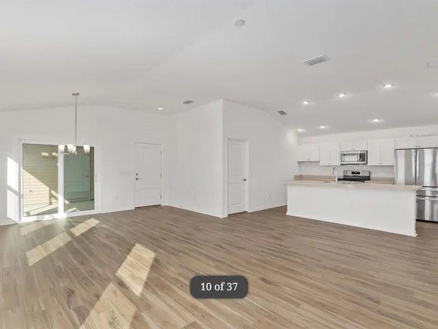 a view of kitchen with kitchen island stainless steel appliances refrigerator stove top oven and cabinets