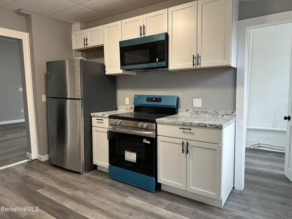 a kitchen with stainless steel appliances granite countertop a stove a refrigerator and a microwave