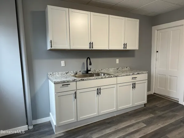a kitchen with granite countertop white cabinets and white appliances
