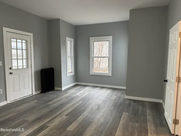 an empty room with wooden floor and windows