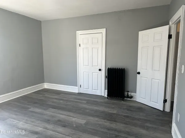 a view of an empty room with wooden floor and closet