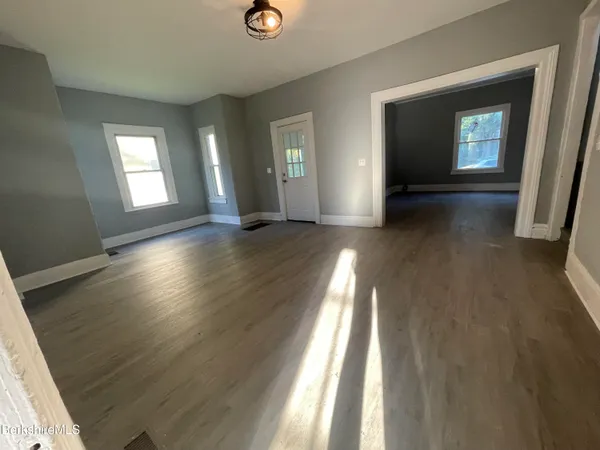 an empty room with wooden floor and windows