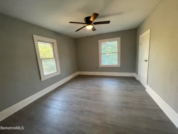 a view of empty room with wooden floor and fan