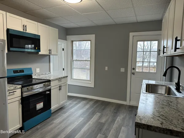 a kitchen with granite countertop a stove and a wooden floor