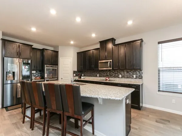 a large kitchen with kitchen island granite countertop wooden cabinets a counter top space and stainless steel appliances