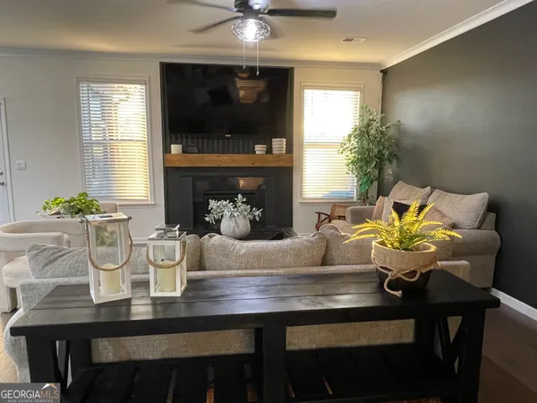 a dining room with furniture a potted plant and a flat screen tv