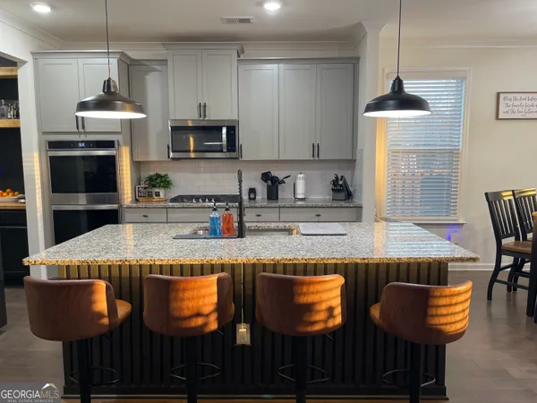 a kitchen with granite countertop kitchen island stainless steel appliances a stove refrigerator and cabinets