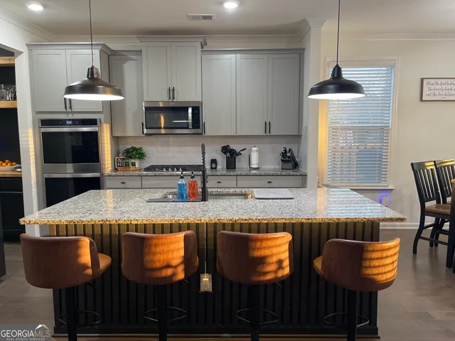 a kitchen with granite countertop kitchen island stainless steel appliances a stove refrigerator and cabinets