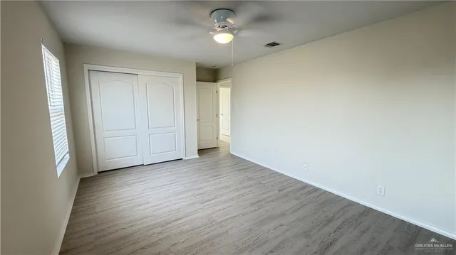 an empty room with wooden floor closet and windows