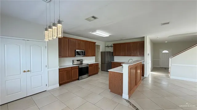 a large kitchen with stainless steel appliances kitchen island granite countertop a refrigerator and a sink