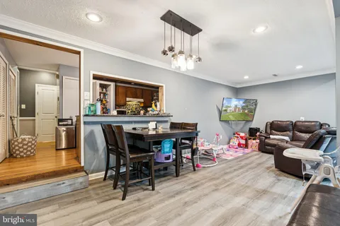 a living room with furniture a dining table and paintings on the wall