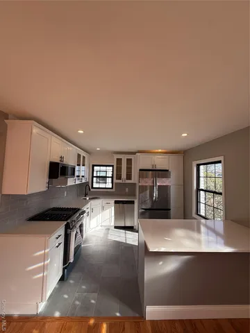 a kitchen with stainless steel appliances kitchen island granite countertop a refrigerator a stove a sink a microwave and island