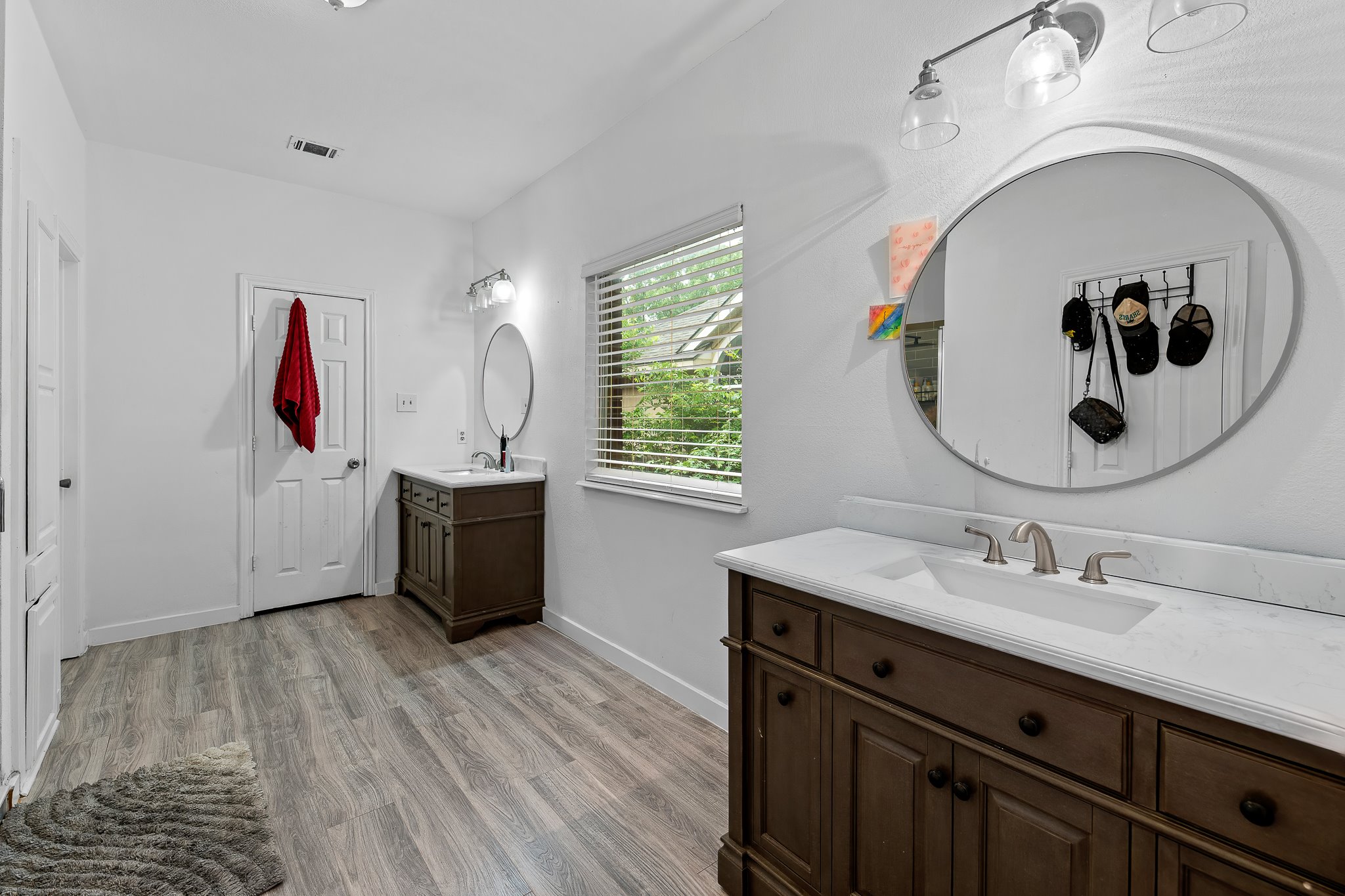 11737 Rydalwater Lane Austin, TX 78754 - Photo 19 of 40 Bathroom featuring wood-finish flooring, dual vanity areas with storage, white countertops, and a window with blinds
