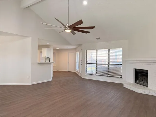a view of an empty room with wooden floor and a fireplace