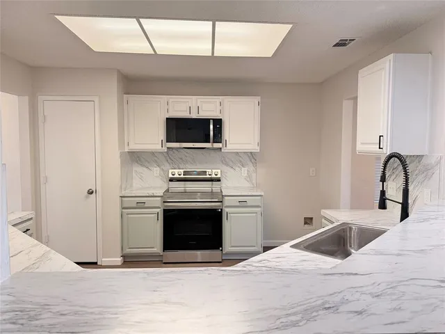 a kitchen with stainless steel appliances kitchen island a stove a sink and a microwave