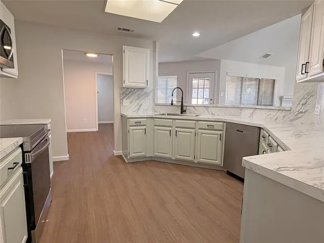 a kitchen with a sink a stove cabinets and wooden floor