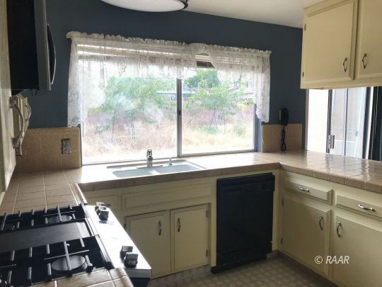 1219 North Erwin Street Ridgecrest, CA 93555 - Photo 5 of 20 a kitchen with kitchen island a counter space a sink a stove and a window