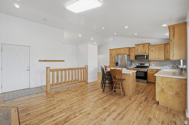 791 East Saddle Road Grantsville, UT 84029 - Photo 12 of 46 Open-concept living space featuring wood-finish flooring, a kitchen island with seating, stainless steel appliances, and wood cabinetry