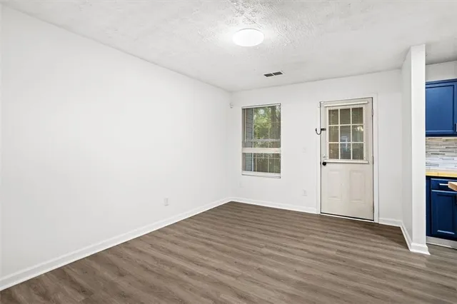 an empty room with wooden floor and windows