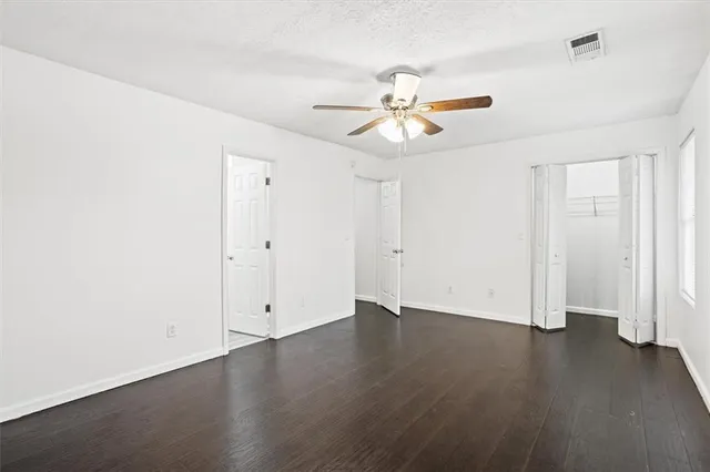 an empty room with wooden floor and ceiling fan