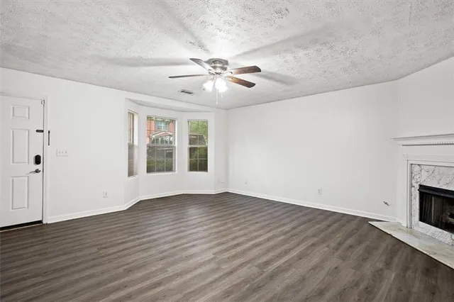 a view of an empty room with wooden floor fireplace and a window