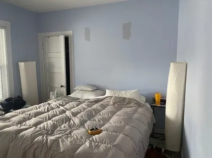 a bedroom with a bed and wooden floor