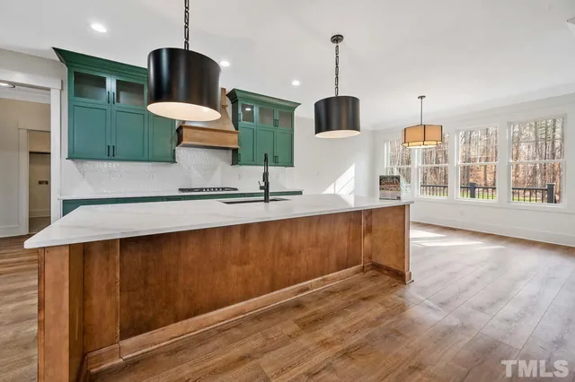 a kitchen with stainless steel appliances kitchen island a stove and a wooden floor