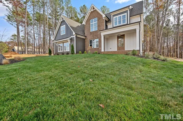 a view of a brick house with a big yard and large trees