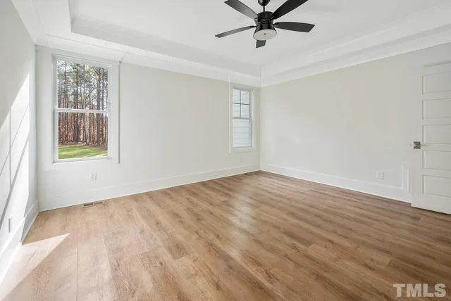 an empty room with wooden floor fan and windows