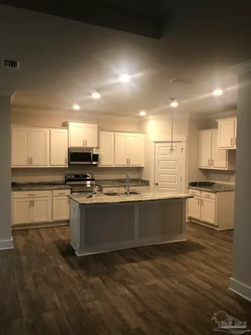 a large kitchen with kitchen island sink stove and white cabinets