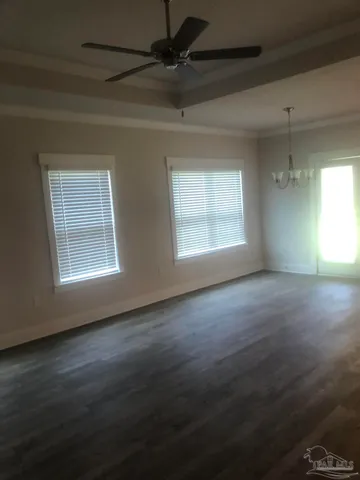 an empty room with wooden floor windows and fan