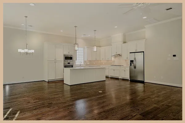 a large kitchen with white cabinets and wooden floor