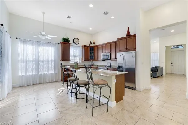 a kitchen with stainless steel appliances granite countertop a sink a stove a refrigerator a center island a stove and a window